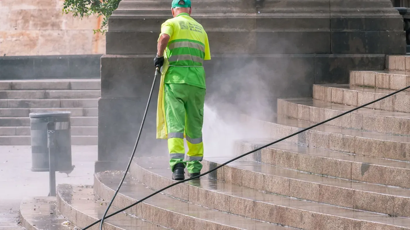 Arbeiter reinigt Steinstufen im Außenbereich mit einem Hochdruckreiniger